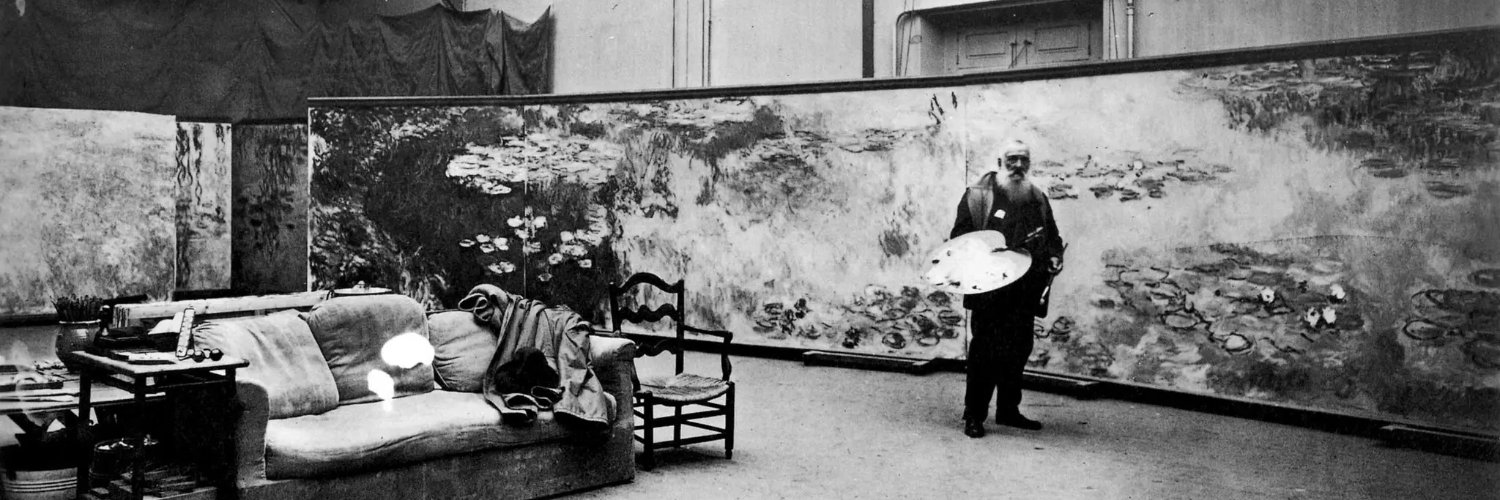 Claude Monet in his studio, standing before large Water Lilies paintings.